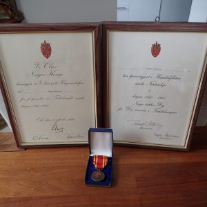 Krigsmedaljen med diplom + Nortraship tjenestegjørings diplom. (Tilhørt krigsseiler Magne Sørhaug fra Tønsberg).